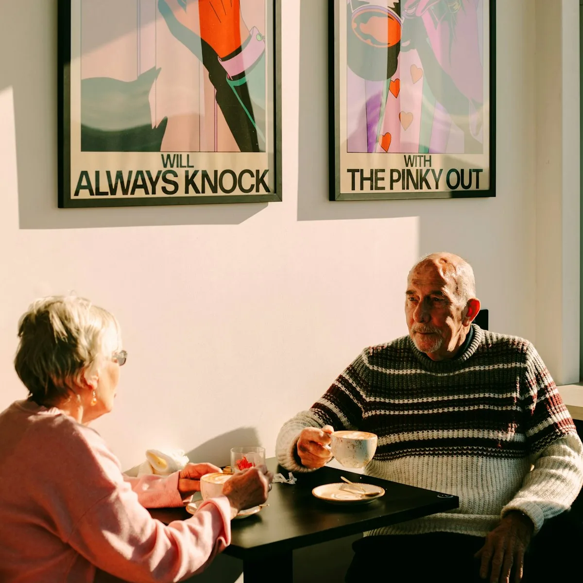 Two customers with coffee at a sunlit table in the Peoples Coffee cafe